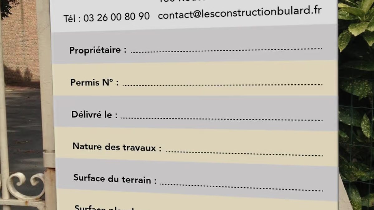 Panneau de permis de construire rempli et fixé en bordure d'un terrain en chantier