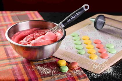 Ustensiles de cuisine originaux et colorés posés sur un plan de travail en bois